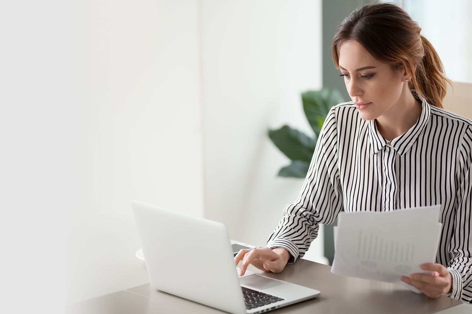 Woman with papers doing work on laptop